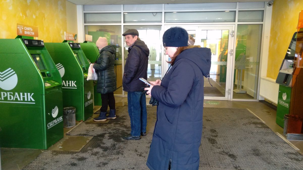 Люди снимают деньги со счетов. Люди стоят у электронных банкоматов фото.